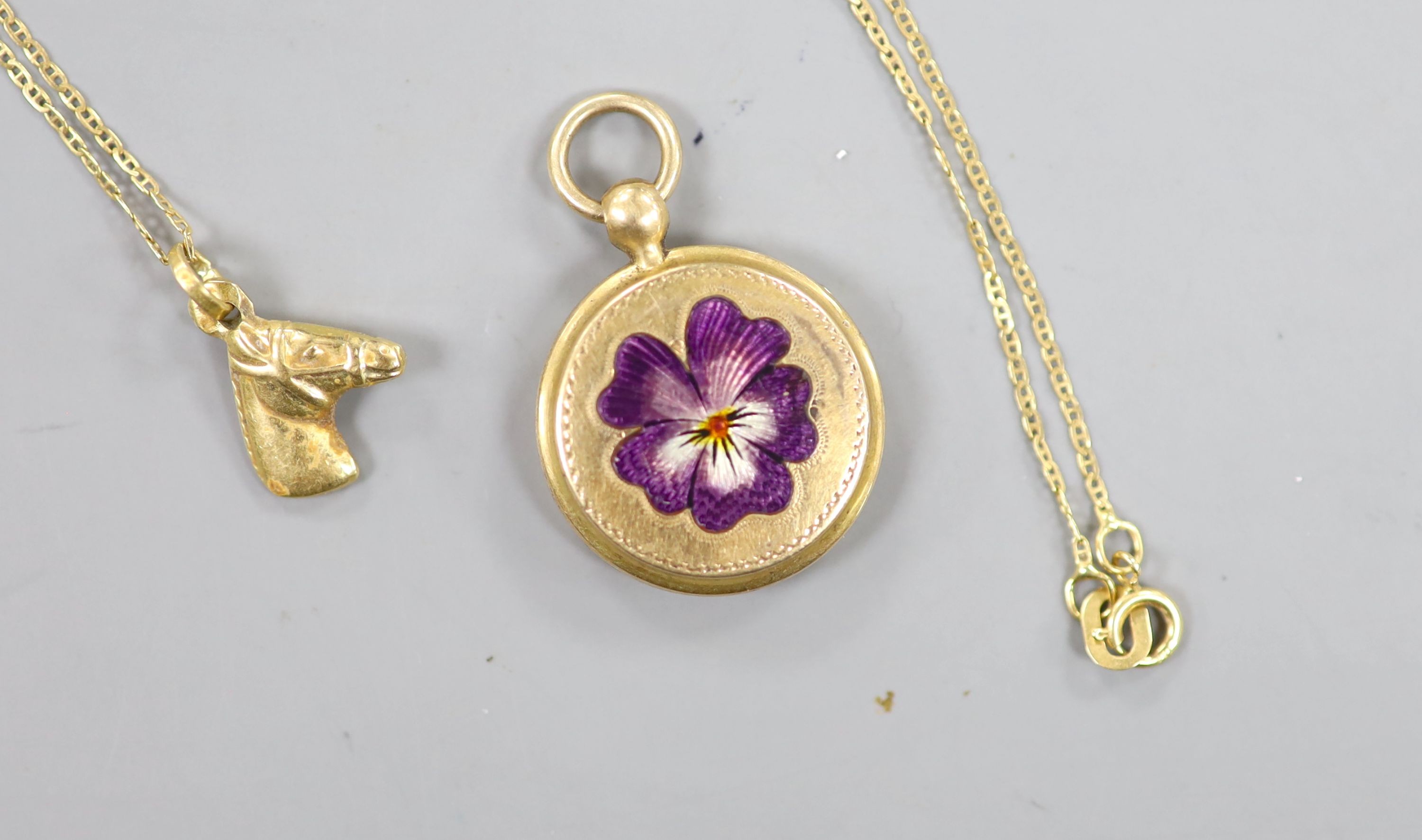 A small early 20th century yellow metal and enamel pendant locket, 18mm, together with a very small horse head pendant on an 18kt fine link chain, gross 5.3 grams.